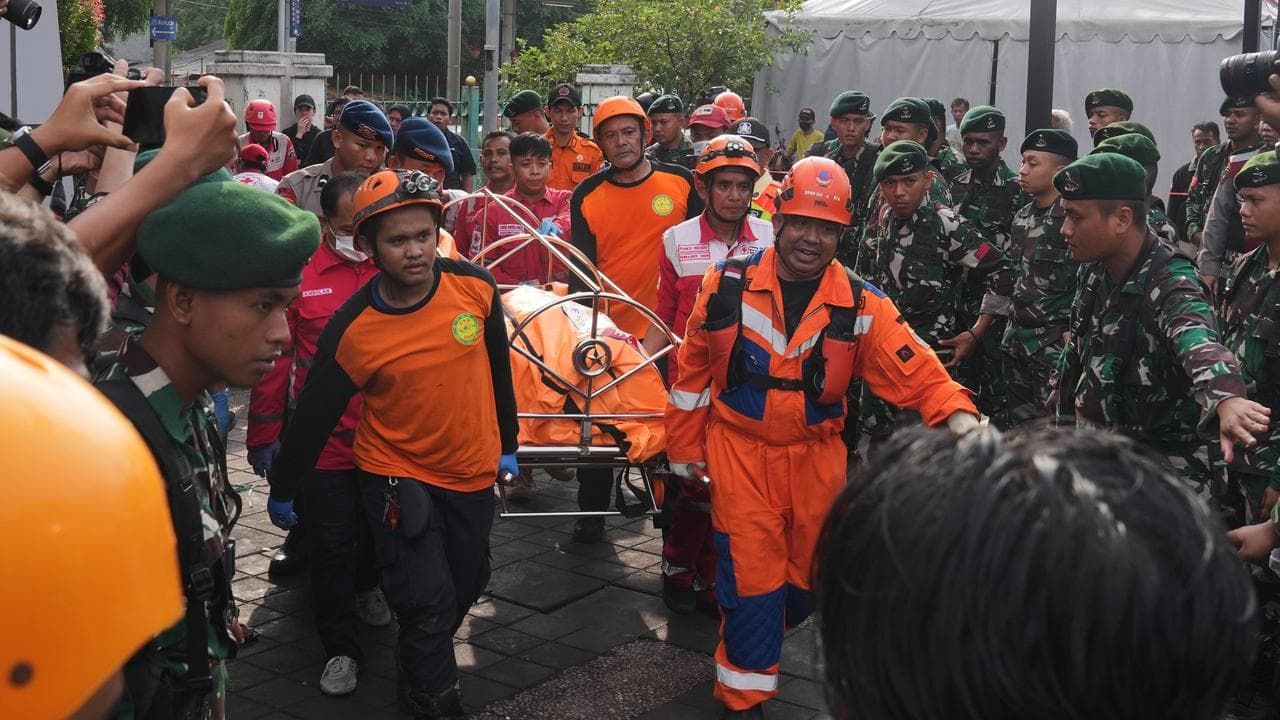 Rescuers carry a body from a train collision in Bekasi, Indonesia