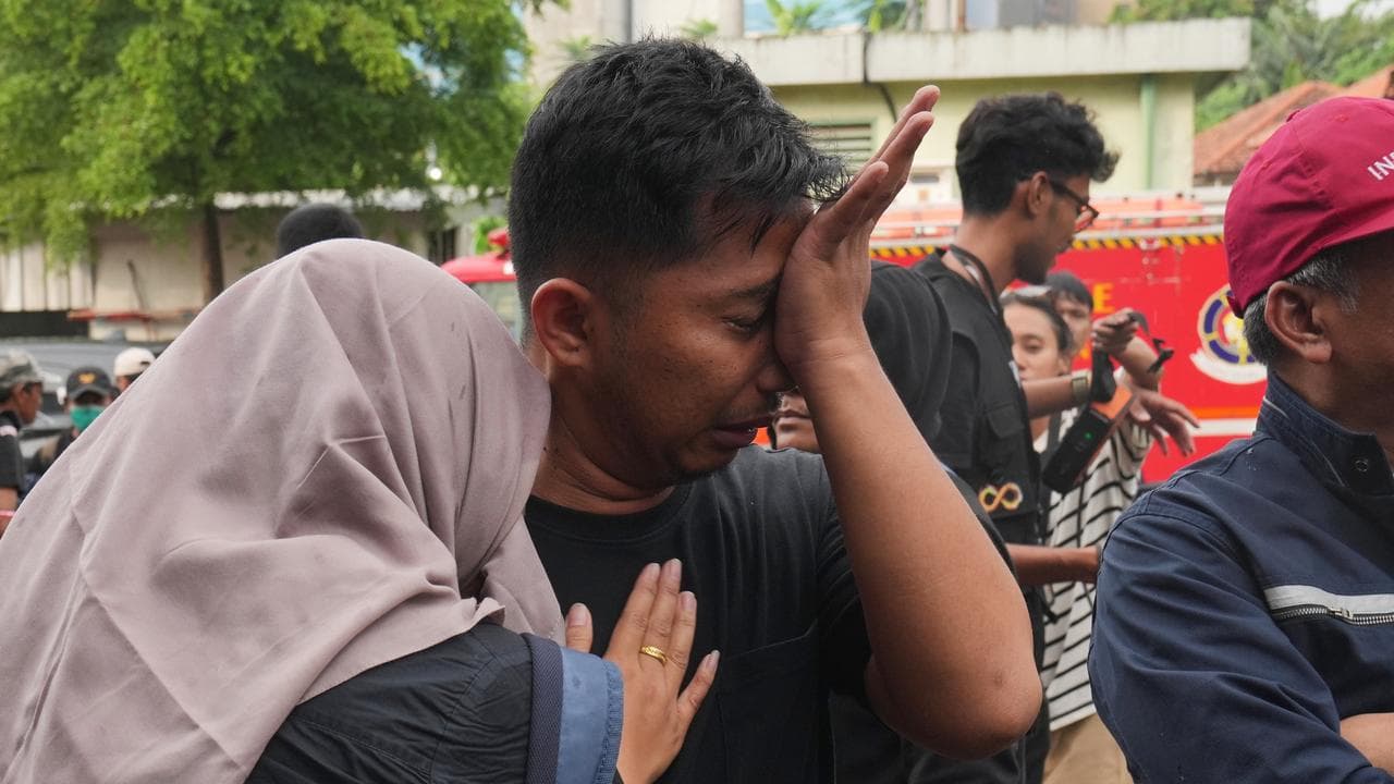 A relative of a victim of a train collision weeps in Bekasi, Indonesia