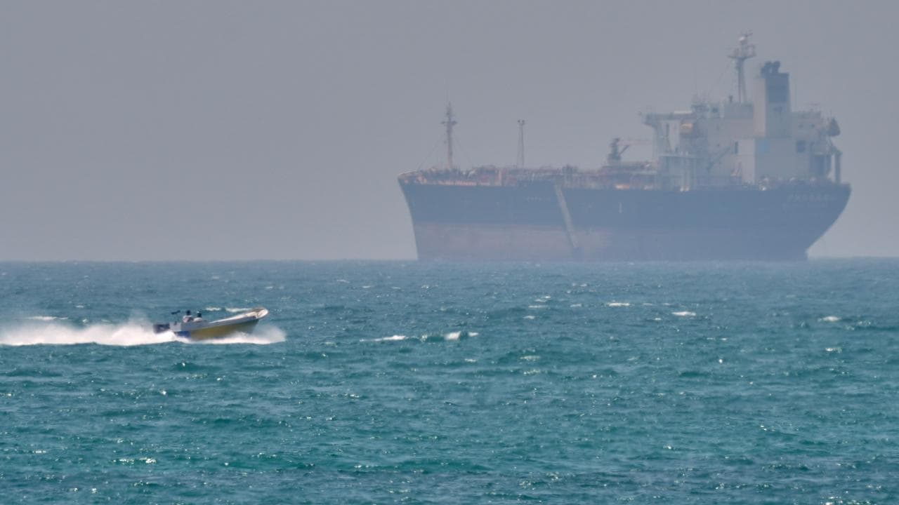 A boat sails past a tanker anchored on the Strait of Hormuz