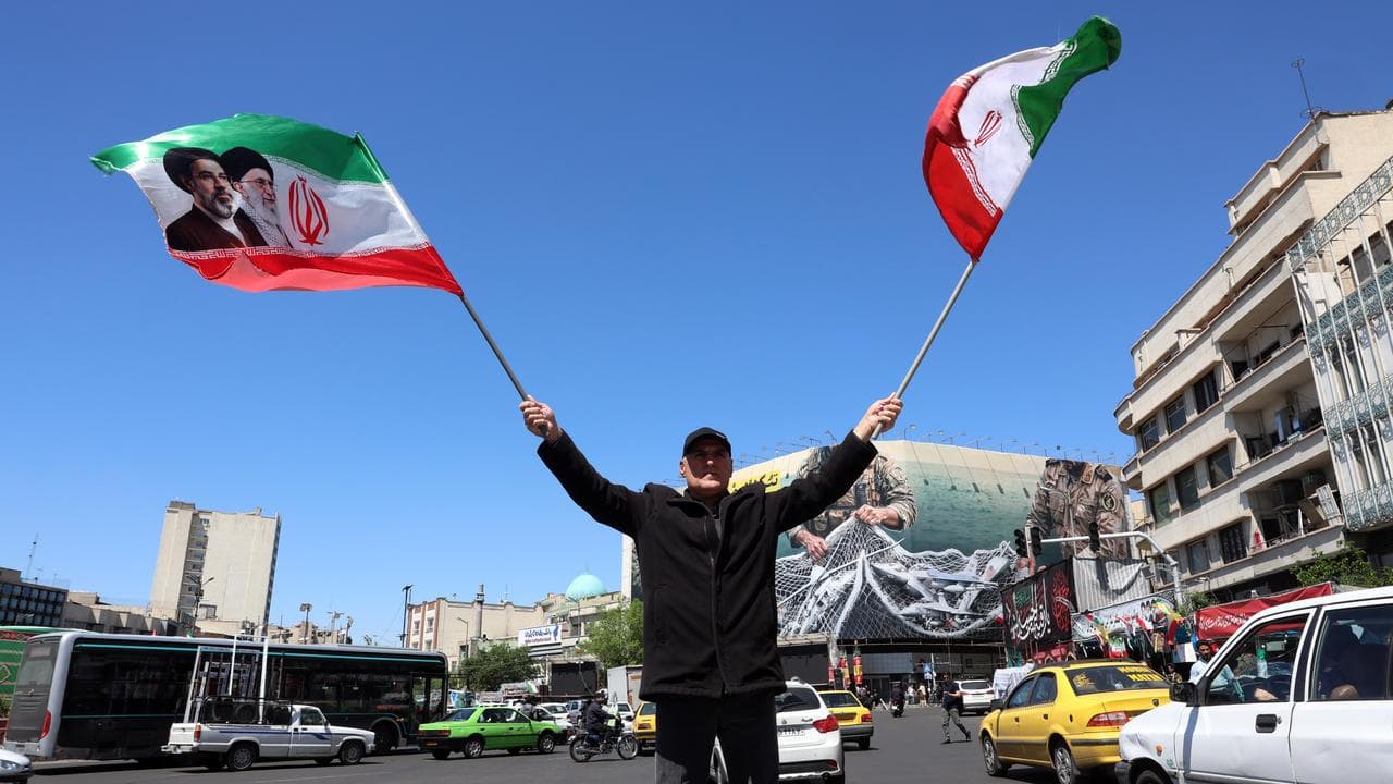 A man waves Iran’s national flags at the Enghelab square in Tehran