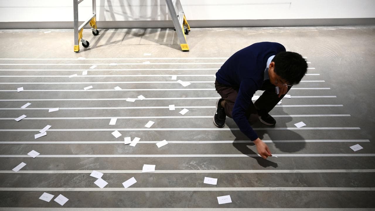 Liu Ding gathers paper words off floor. 