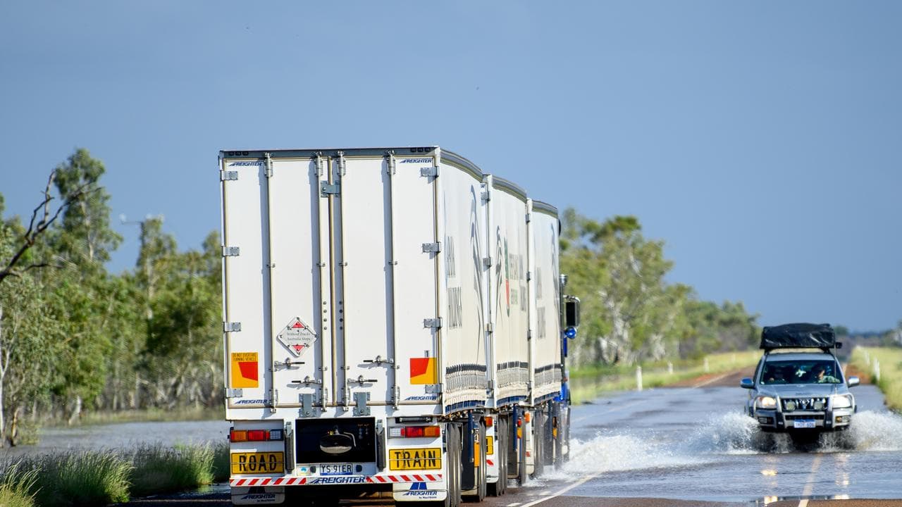 Trucks drive through flood water on Stuart Highway
