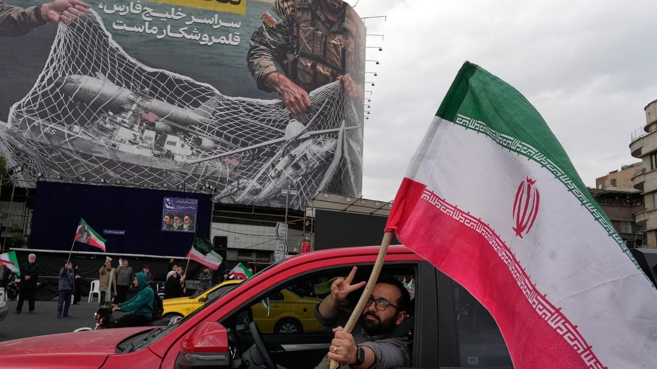 A man waves an Iranian flag in front of an anti-US billboard in Tehran