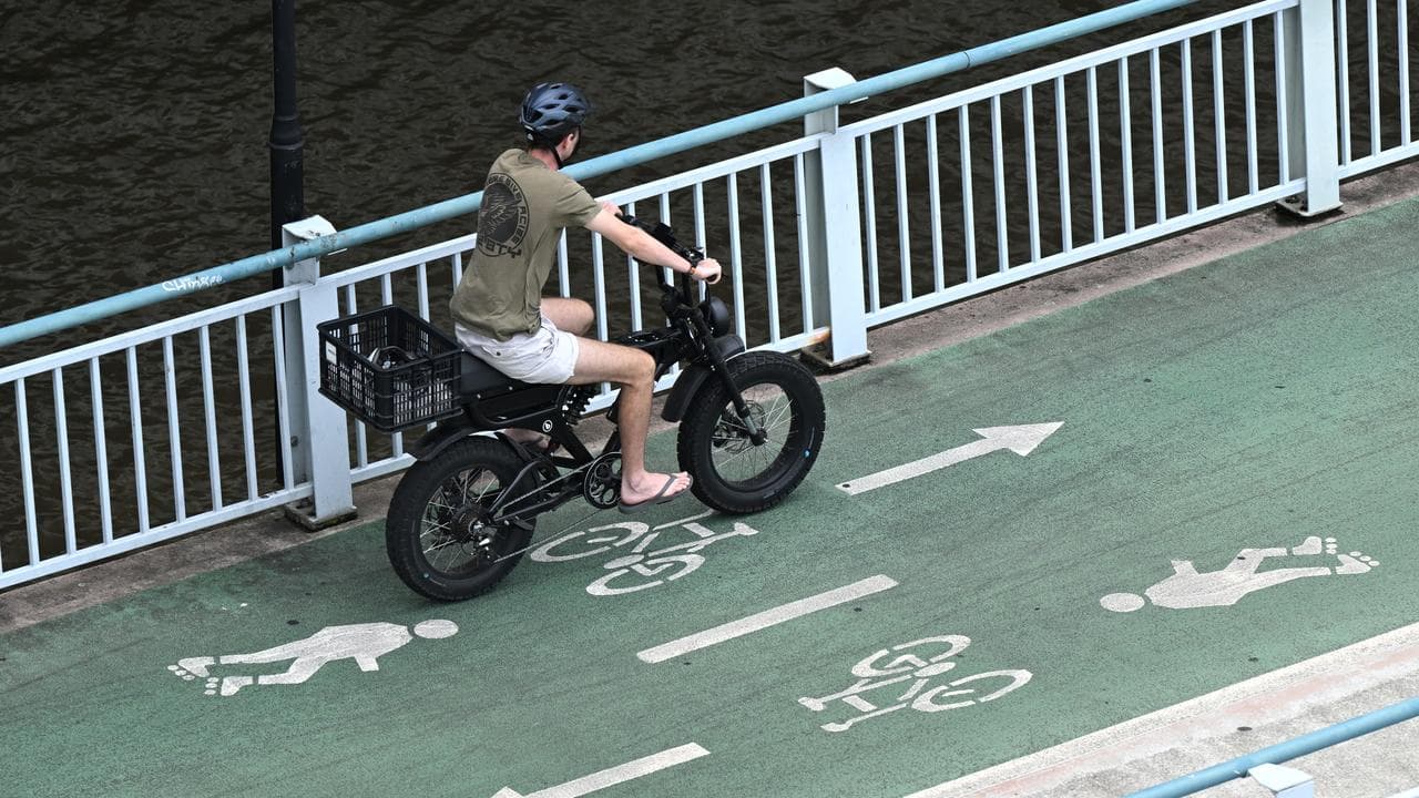 A cyclist rides an e-bike in Brisbane