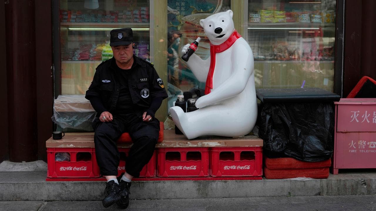 A security guard next to a Coca Cola mascot in Beijing