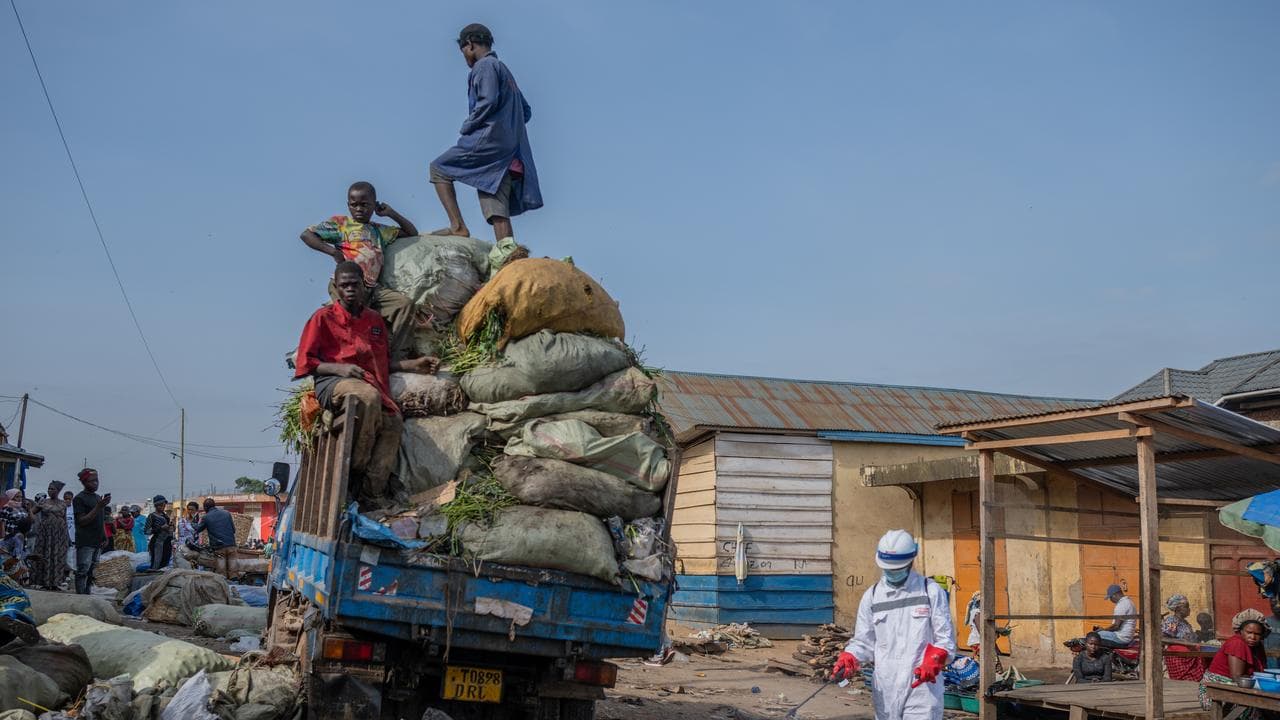 A sanitation worker in a market next to a rubbish truck