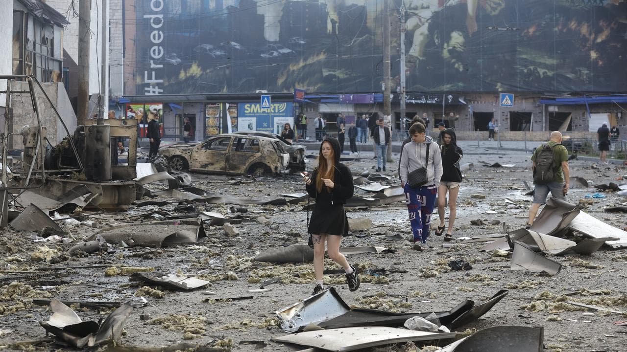 People walk among the debris at the site of shopping centre