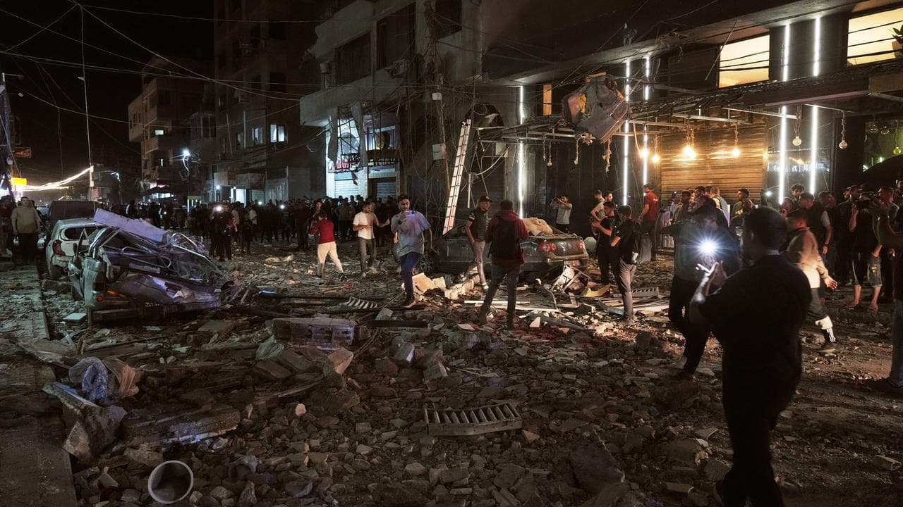 Palestinians inspect the site of an Israeli air strike in Gaza City