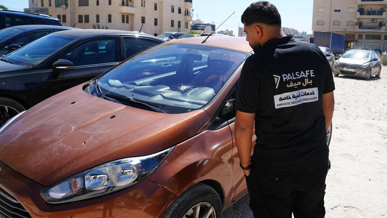 A man inspects the shattered vehicle of Sam Fahd Abu Heikal's family