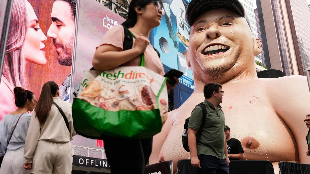 A large inflatable figure depicting Elon Musk stands in Times Square