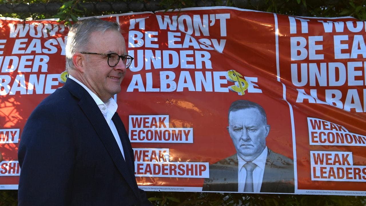 Anthony Albanese walks past political advertising (file image)