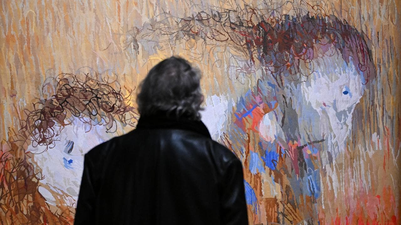 A guest takes a look at a tapestry
