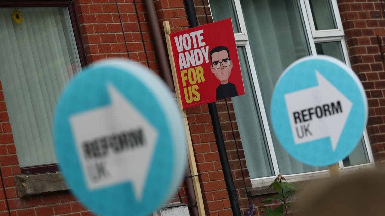 Placards supporting Reform UK and Labour candidate Andy Burnham