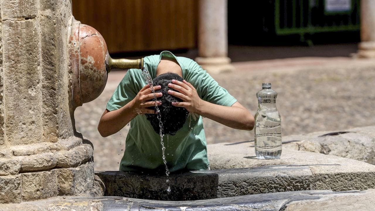 A tourist cools off at a fountain in Cordoba, Spain