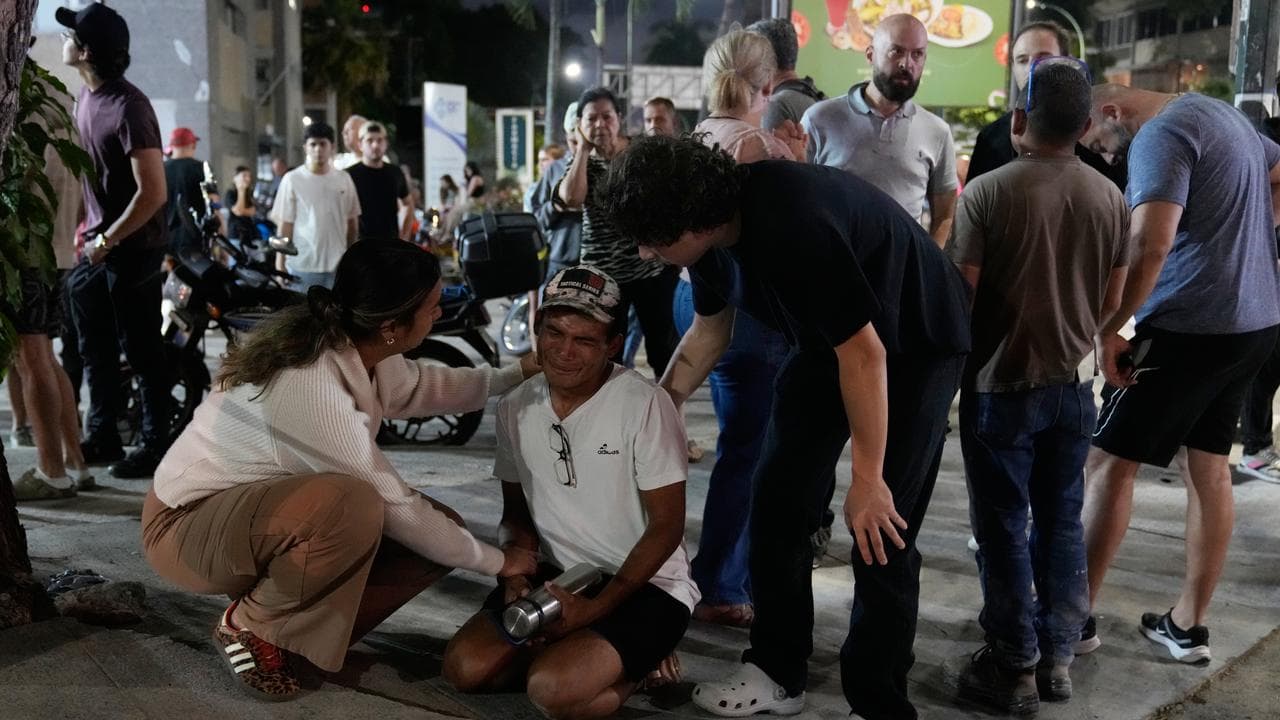 Residents console a man after earthquakes in Caracas, Venezuela