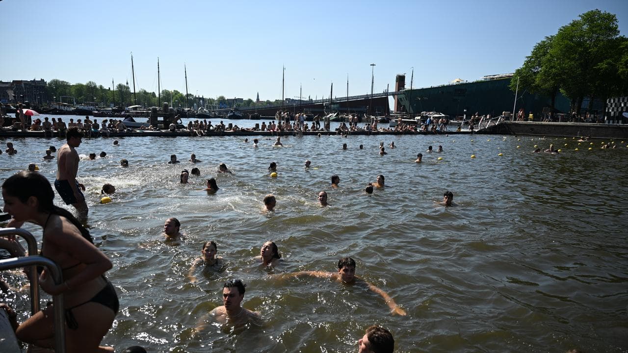 People swim in a canal during warm weather in Amsterdam, Netherlands