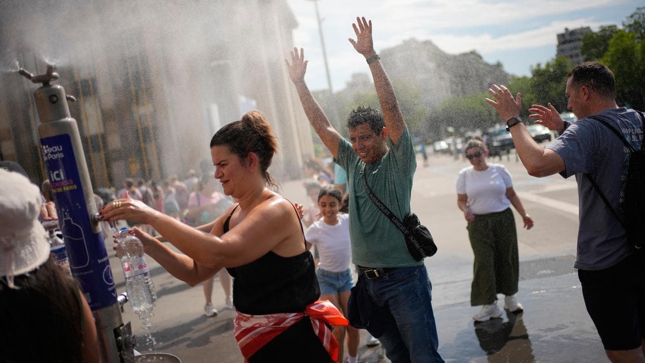 Tourists enjoy cooling off at a public water fountain In Paris