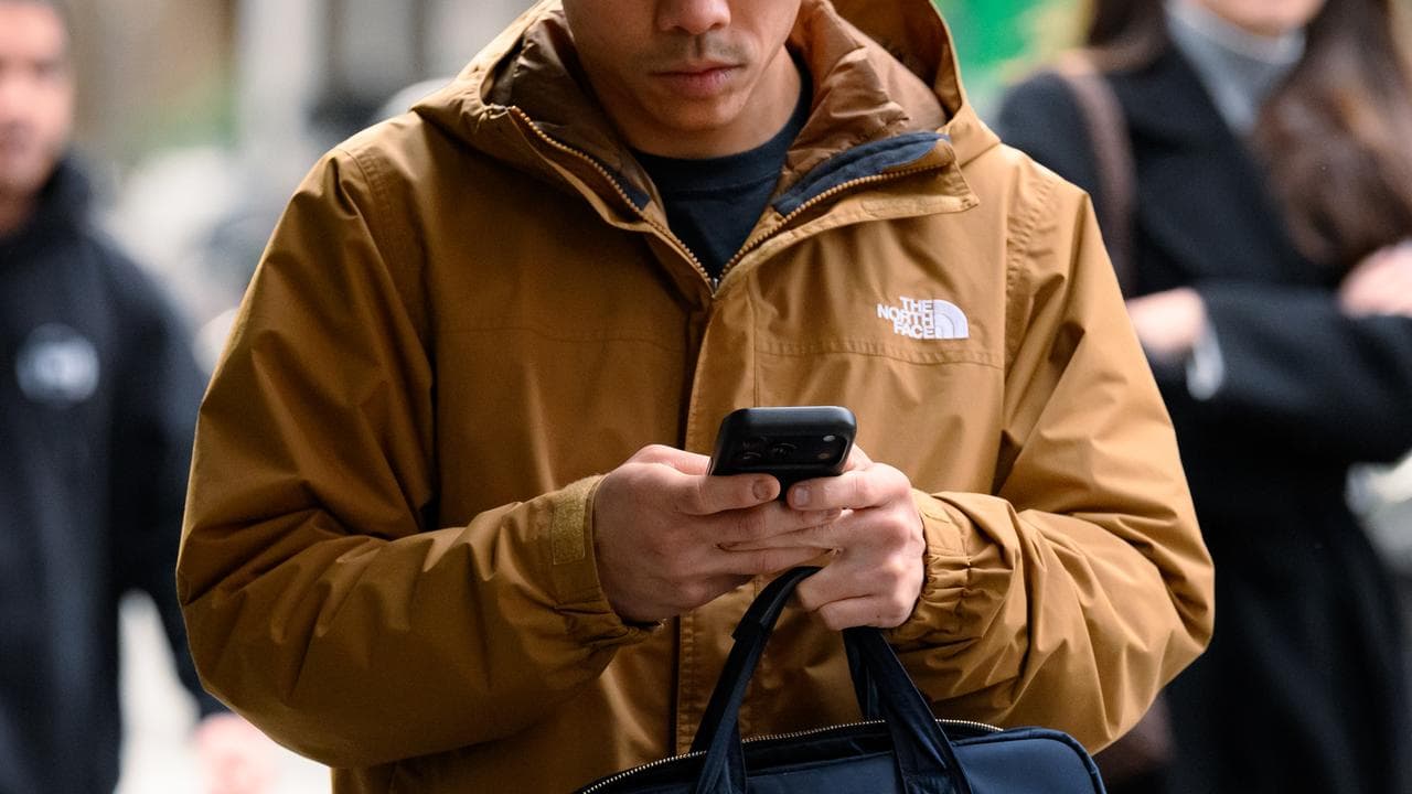 A person walks on the street while holding a phone