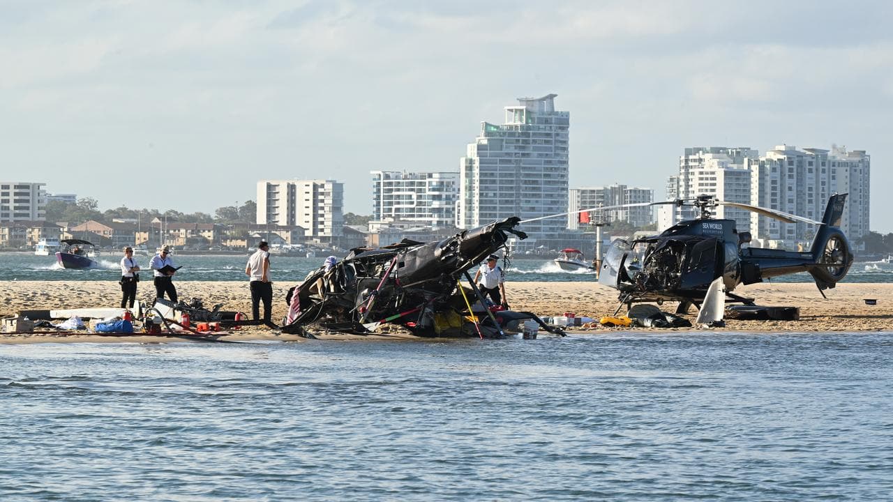 two helicopters , one upside down, on a beach