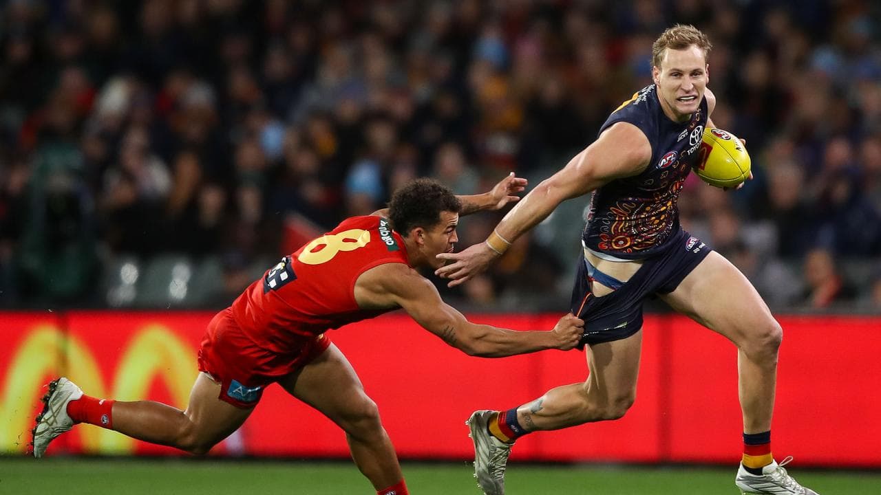 Jordan Dawson of the Crows is tackled by Leonardo Lombard