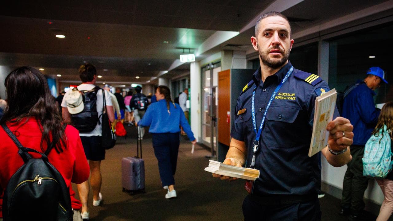 Border Force official hands out incoming passenger cards