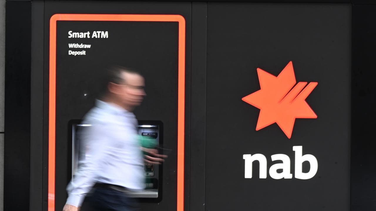 A person is seen walking past a NAB ATM.
