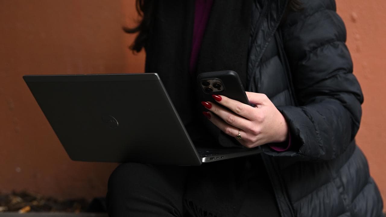 A person holds a mobile phone and laptop (file image)