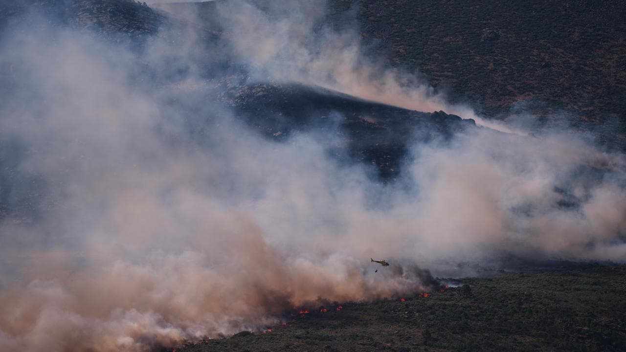 A helicopter drops water on a wildfire in Avila province, Spain