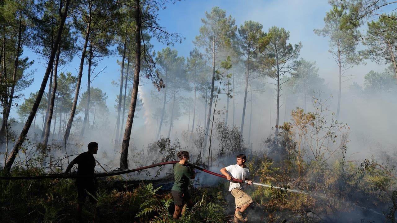 A group hold a firehose and try to suppress a fire near Bordeaux