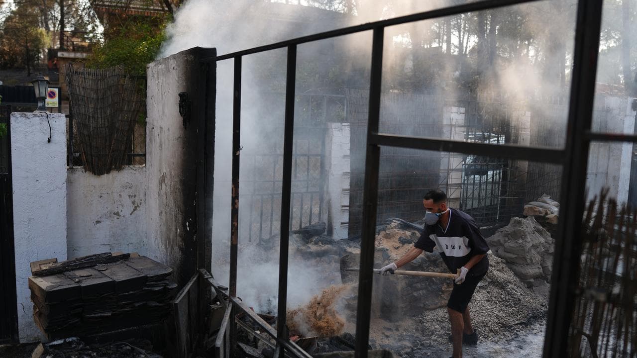 Moha Haddad tries to put out a fire at his home in Avila province