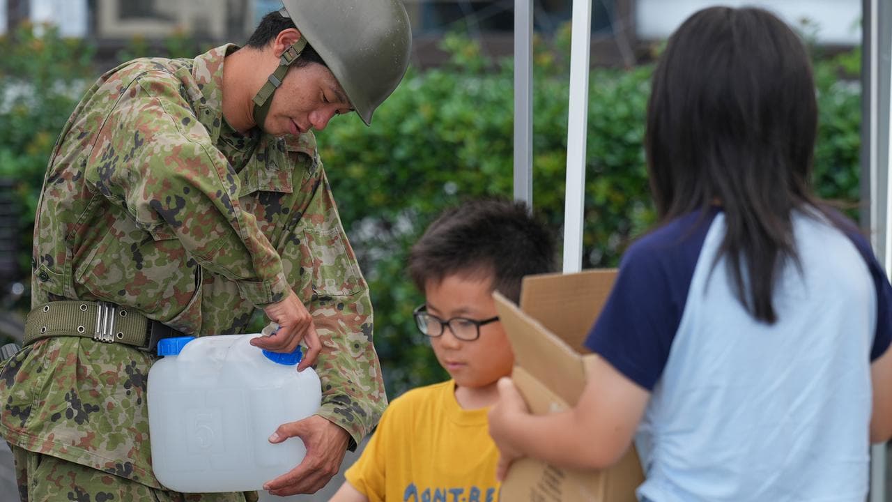 A Self-Defense Force member helps provide water to quake-hit residents