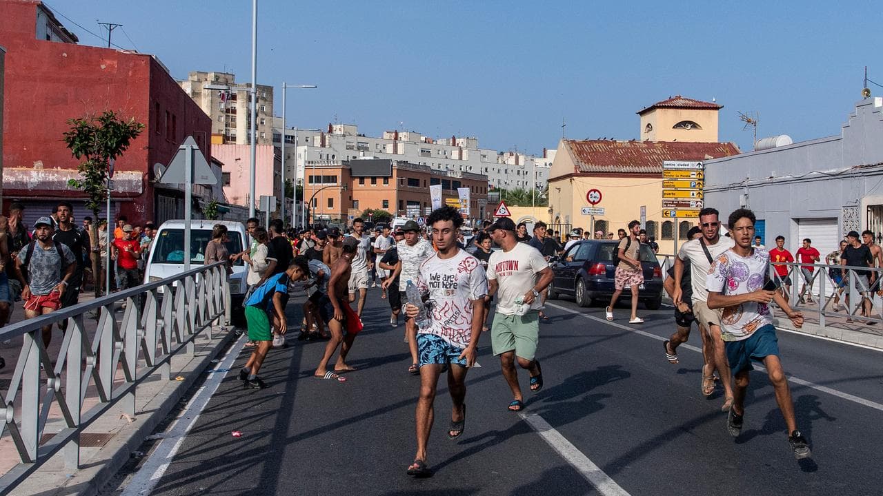 Migrants run from Spanish police in Ceuta after crossing from Morocco