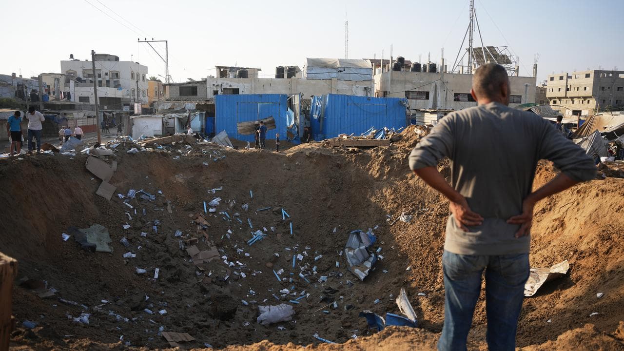 People inspect the scene of an Israeli air strike in Deir al-Balah