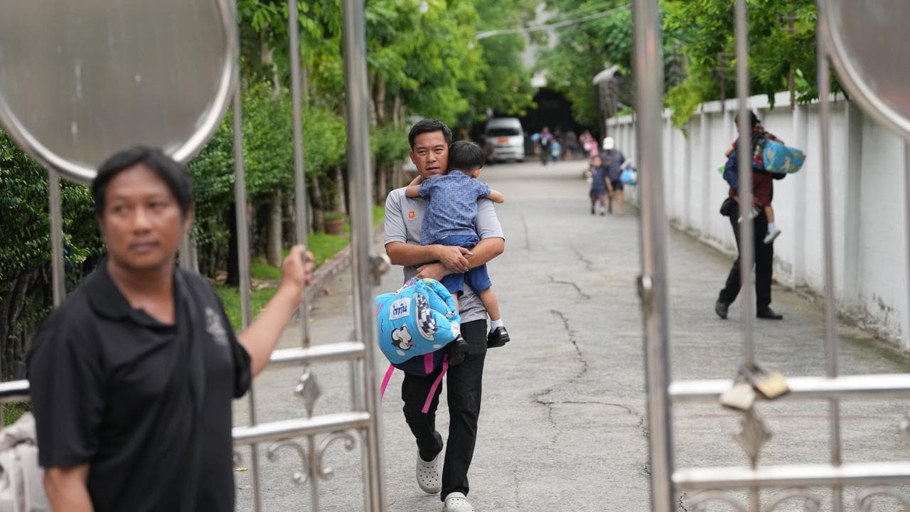 A parent leaves with his child after a school shooting in Thailand 