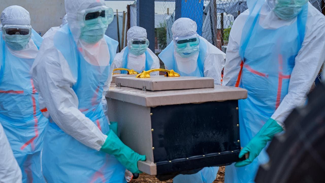 Health staff lift a coffin into a vehicle in Bunia, Congo