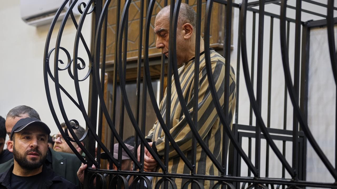 Atef Najib in the defendant's cage in Damascus, Syria