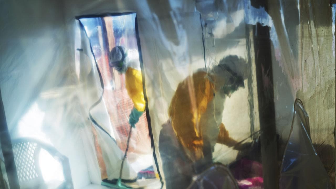 Health workers wearing protective suits tend to an Ebola victim