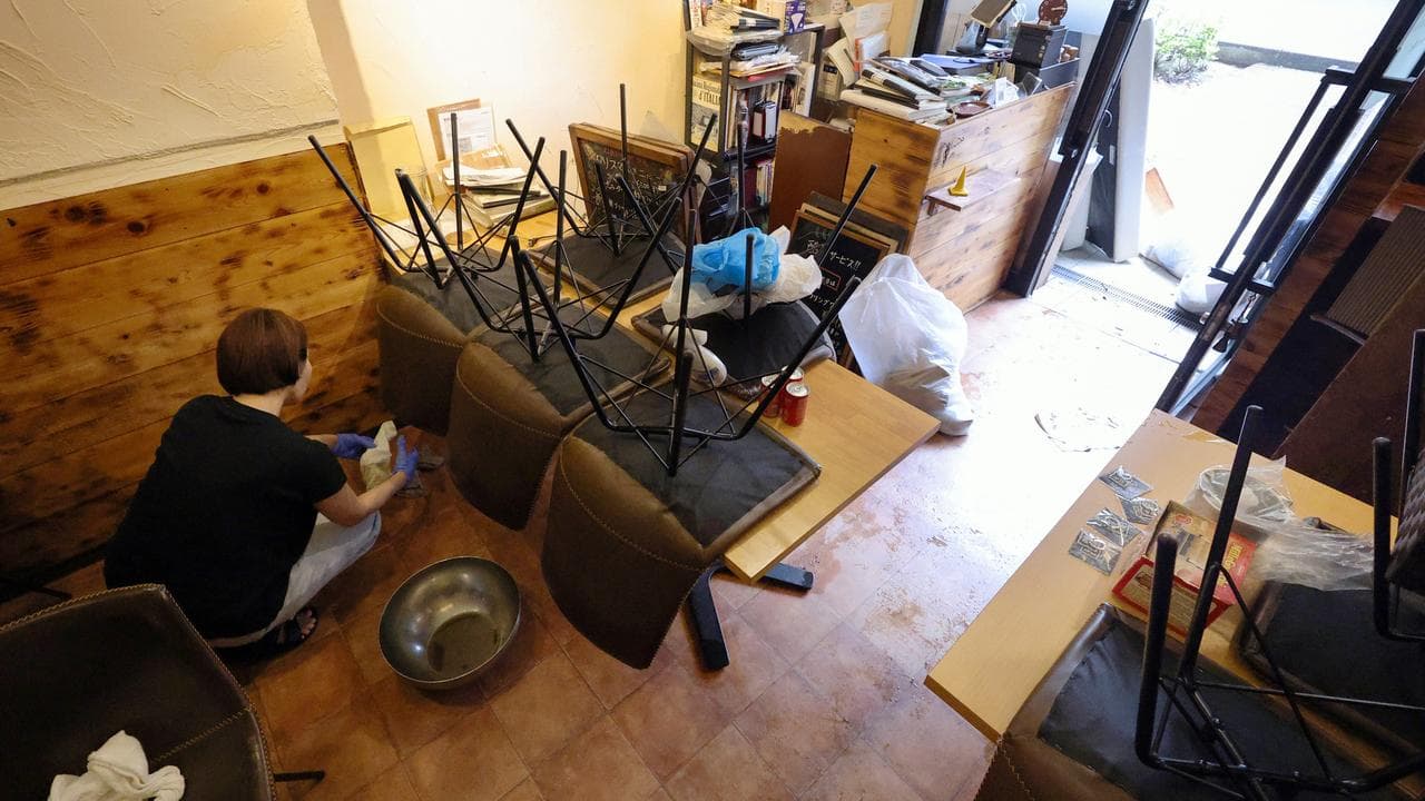 A woman cleans up a flooded restaurant in Chiba, Japan