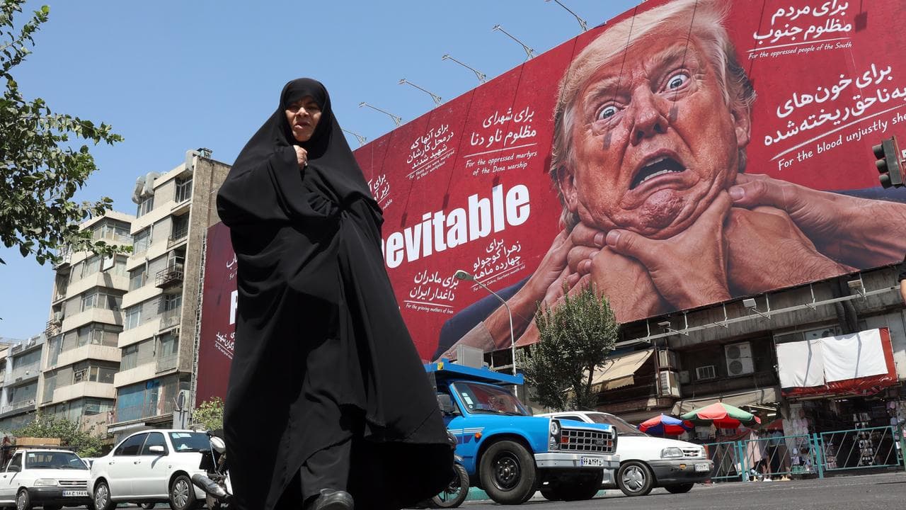 A woman walks next to an anti-Trump billboard in Tehran, Iran