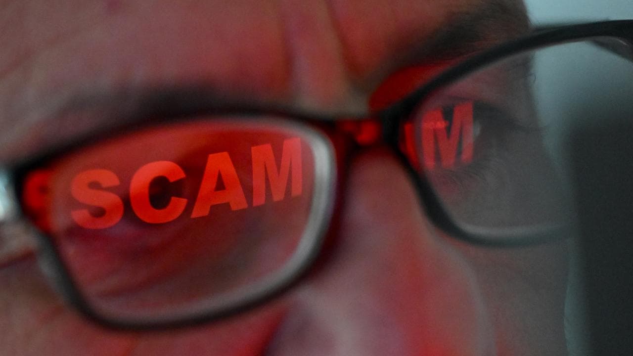 The word ‘scam’ reflected in a person’s glasses (file image)