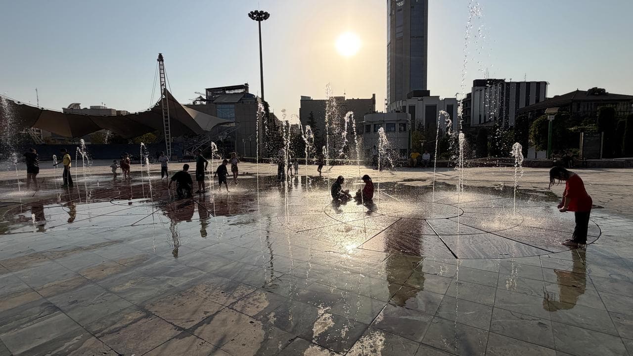 Children enjoy a water fountain at a water park in Tehran
