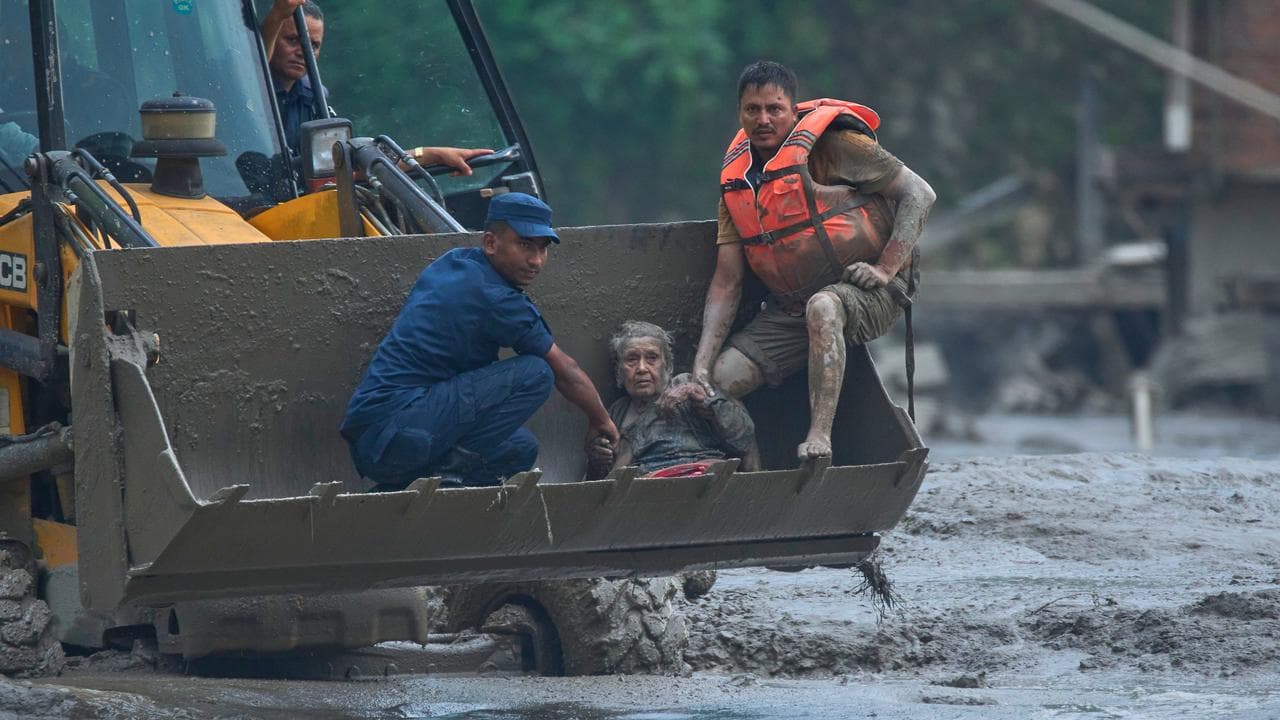 Rescuers use an earthmover to save a woman from floods.