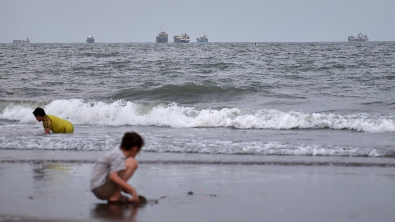 Children play at the beach with boats in the strait out at sea