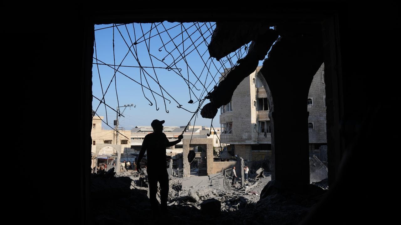 People inspect damaged buildings in Gaza Strip