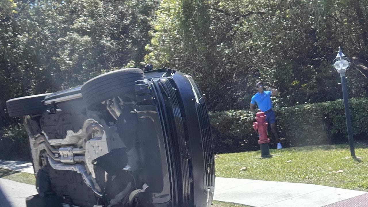 Golfer Tiger Woods stands by his overturned vehicle