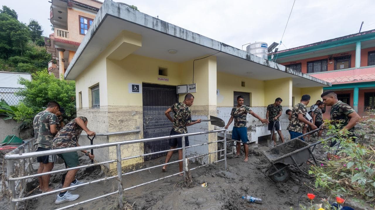 Members of the Nepal Army shovel mud