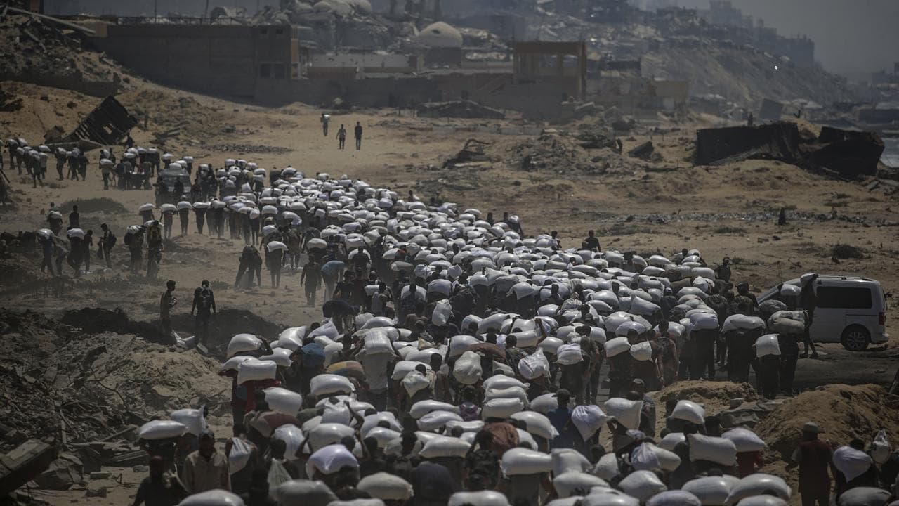 Palestinians carry food aid in northern Gaza, 27 July 2025.