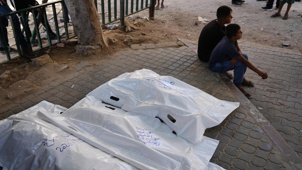 Palestinians sit beside the bodies of members of the Ahmed family