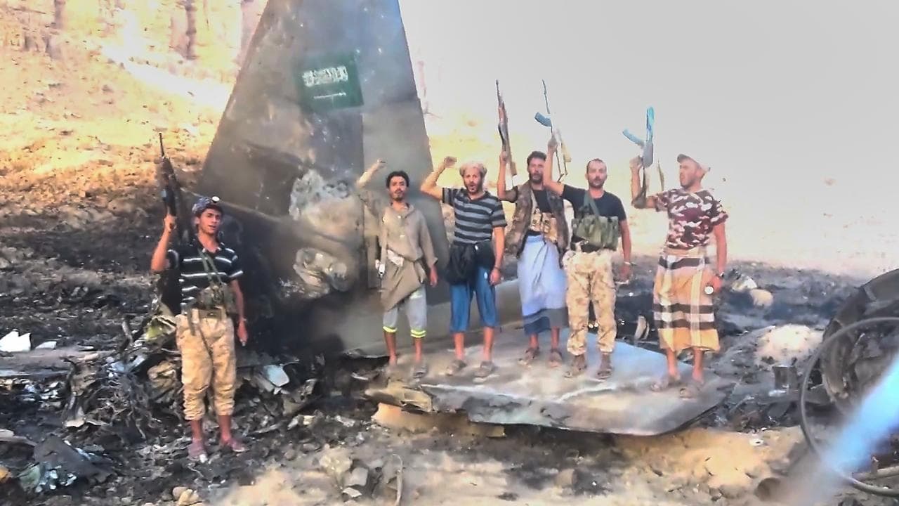 Houthi fighters posing with the wreckage of a Saudi F-15 fighter jet