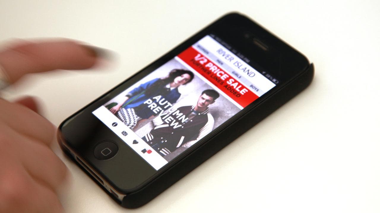 A woman browses an online clothing store on her iPhone
